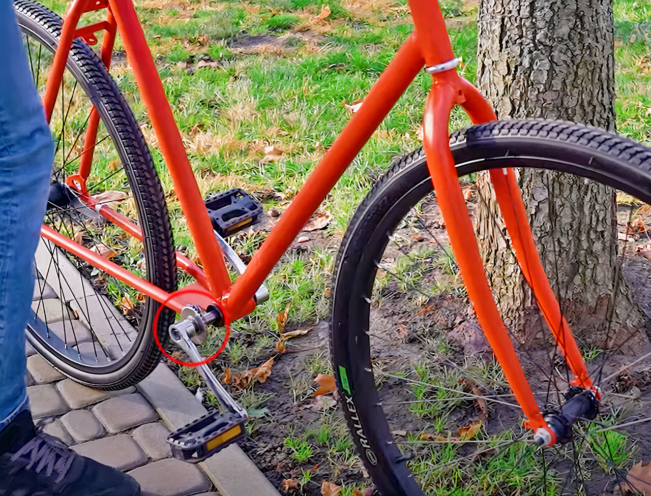Orange and black chainless bicycle in a garden