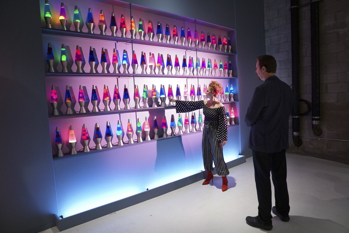 A lady showing lava lamps wall to a man