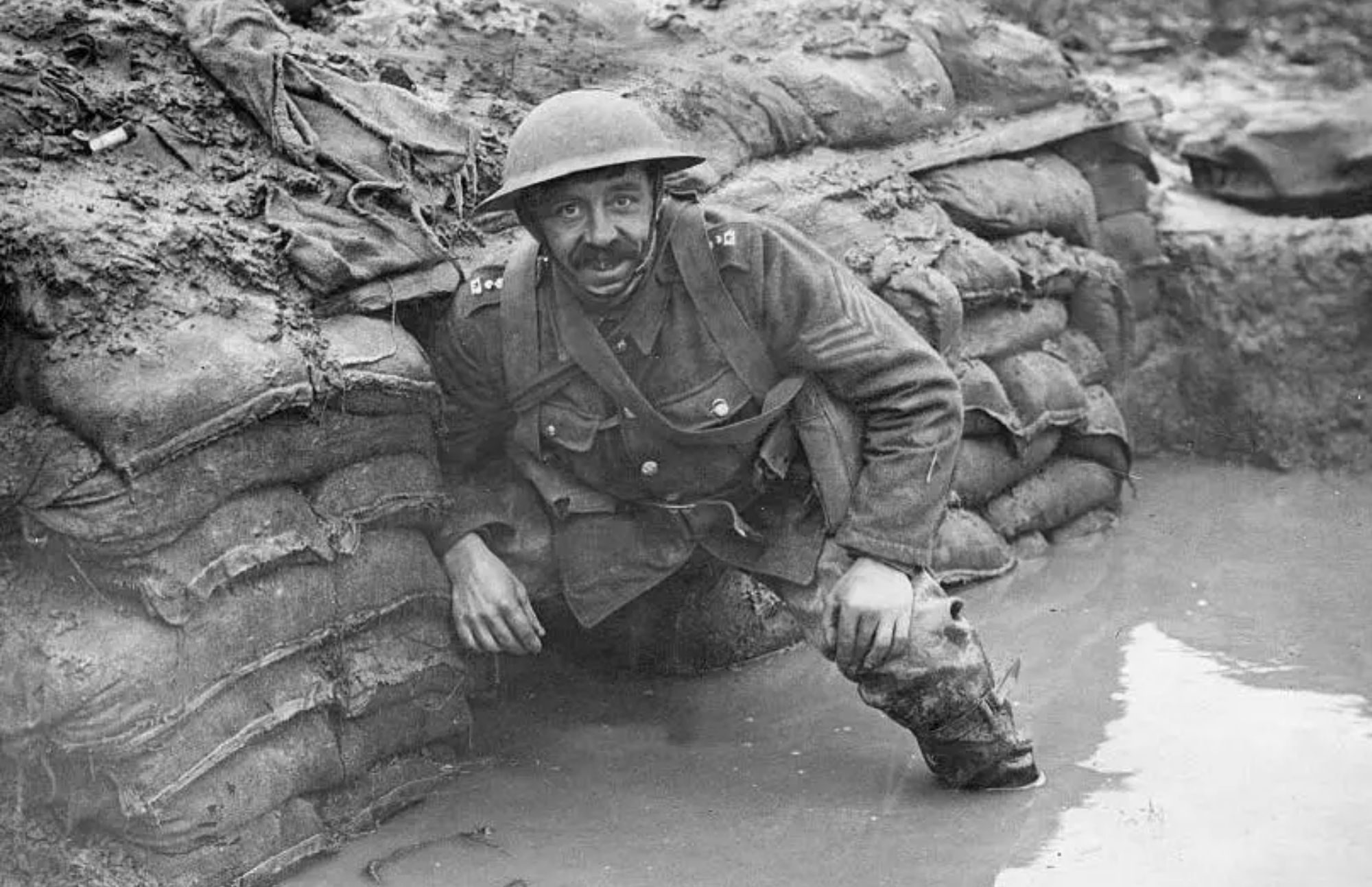 Soldier wearing a hard hat with his feet submerged in mud and water