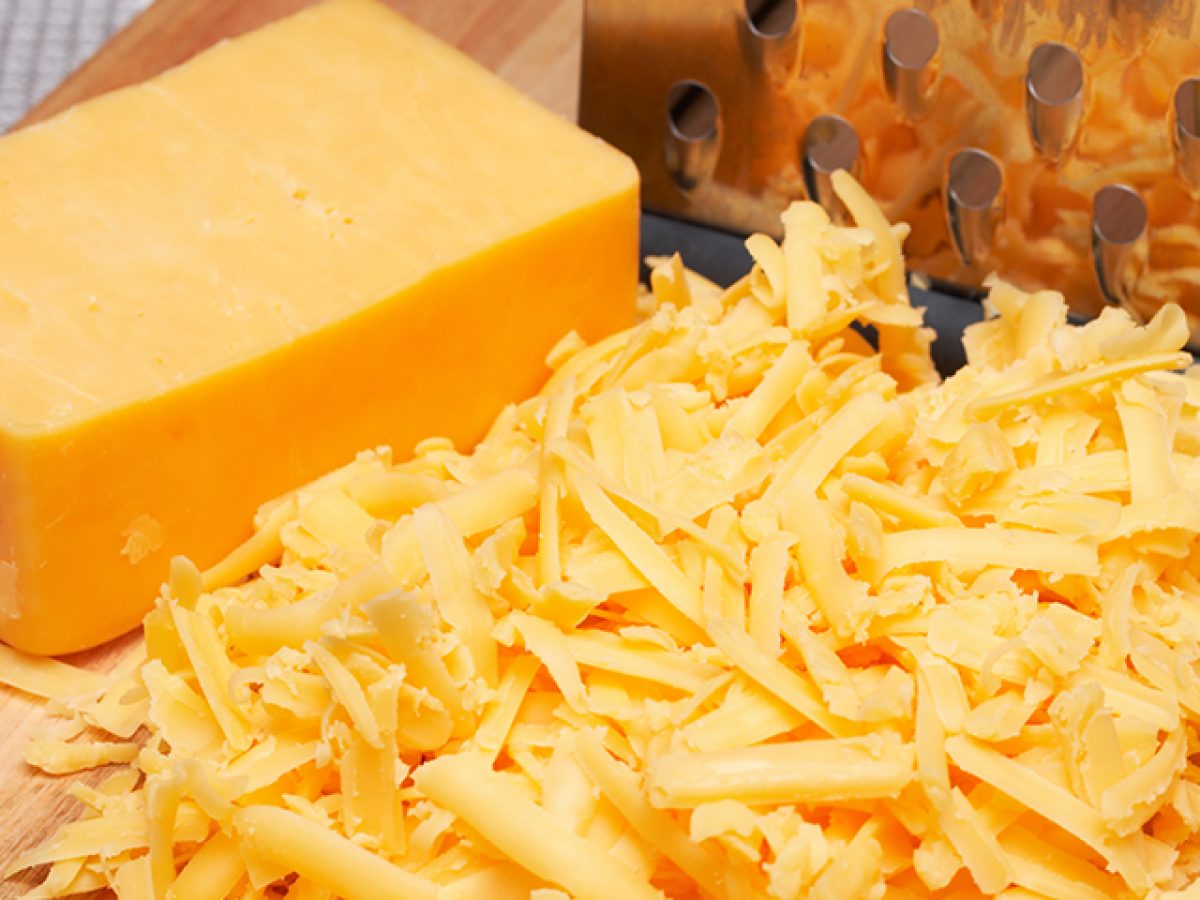 A thick sliced and grated cheese with a metal grate on the side