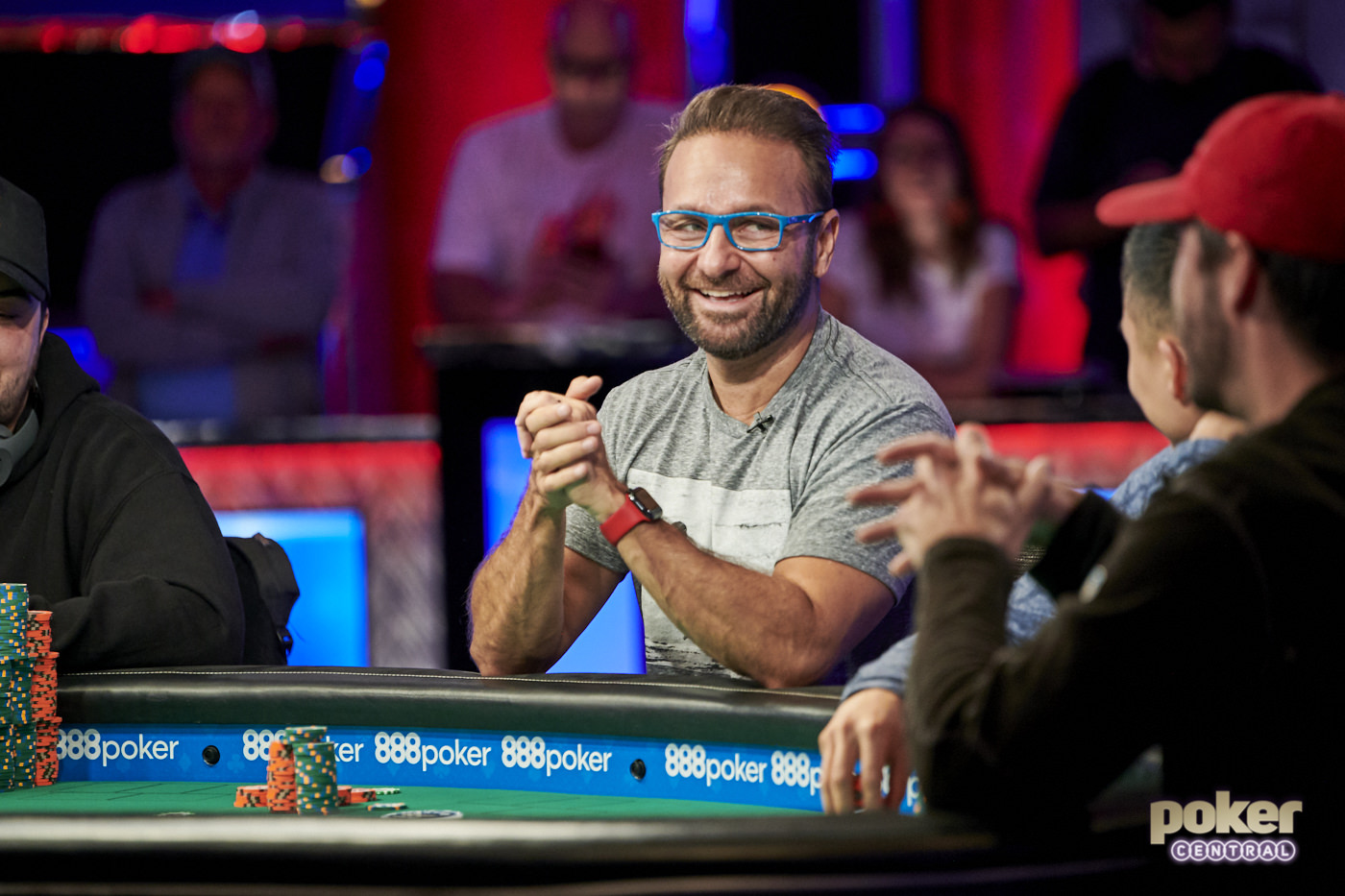 Daniel Negreanu is smiling and looking on his co-poker player while showing his hands crossed