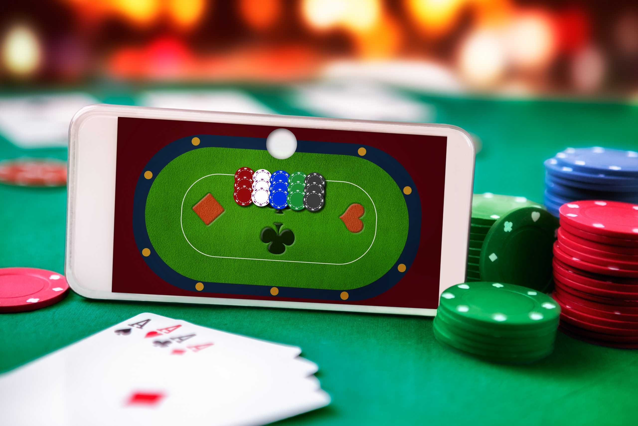 Poker game on phone, poker cards, and poker coins on a green table