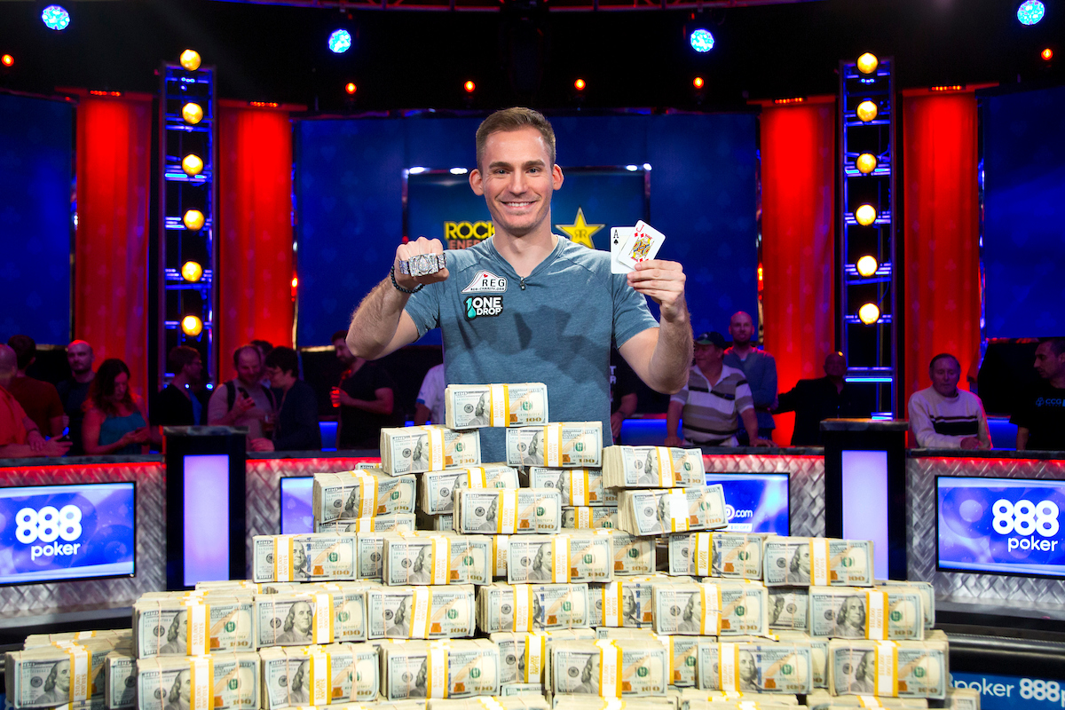 Justin Bonomo is in front of piles of money and smiling at the camera