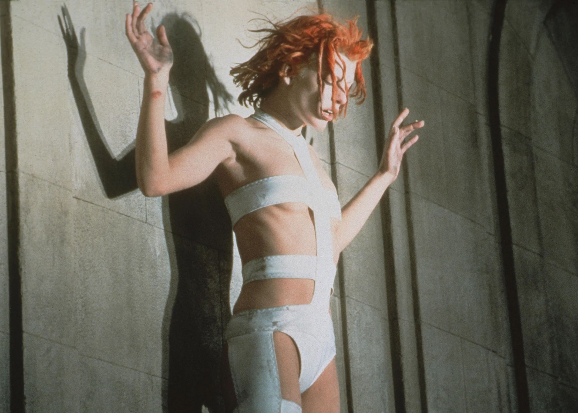 Milla Jovovich wears a white bandage bodysuit and an orange colored hair