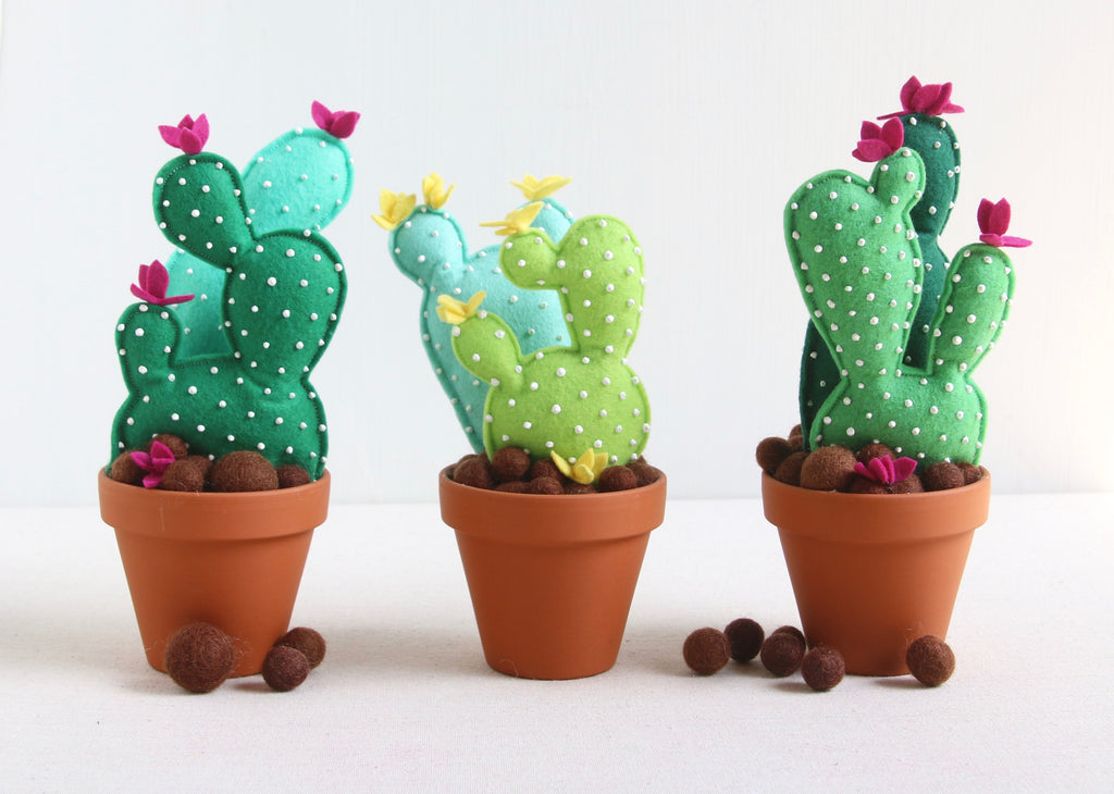 Three artificial cactus made of sheet of felt and some brown balls in the surface