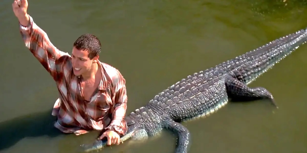 A man holding the mouth of an alligator in the lake
