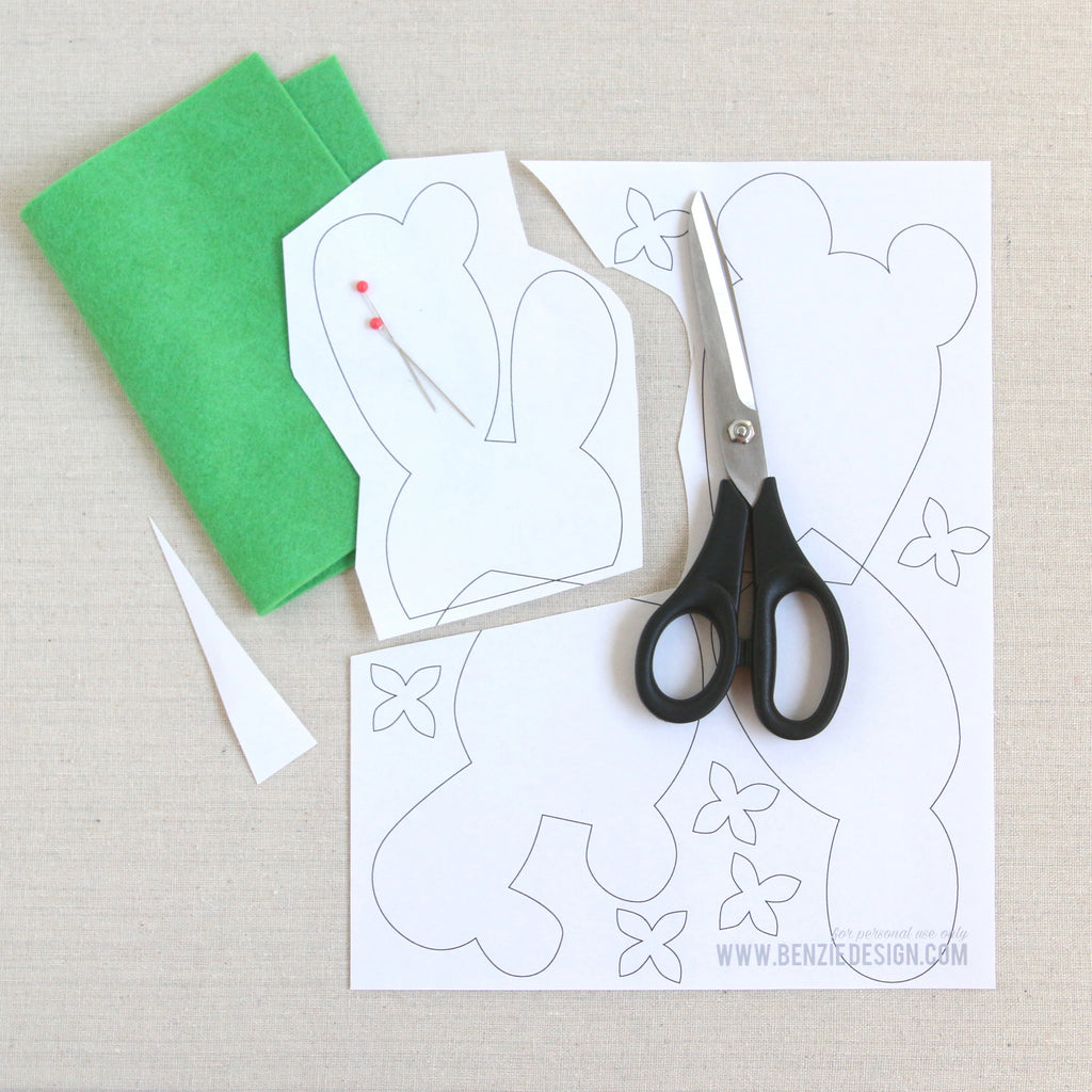 A green sheet of felt, cactus pattern, and a scissor on top of the paper