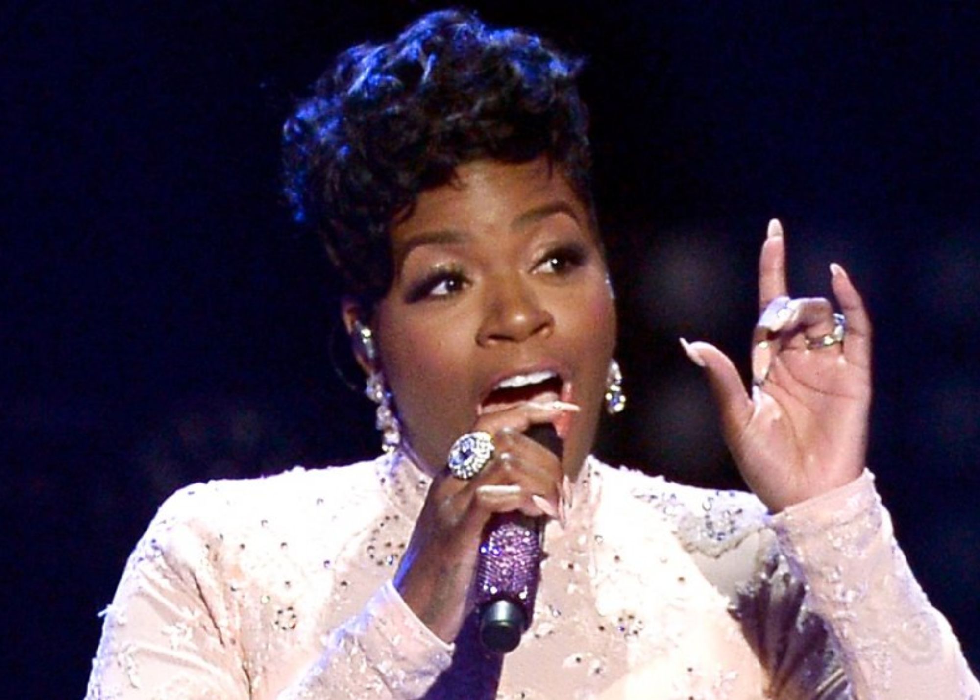 Fantasia holding a microphone while singing infront of many people