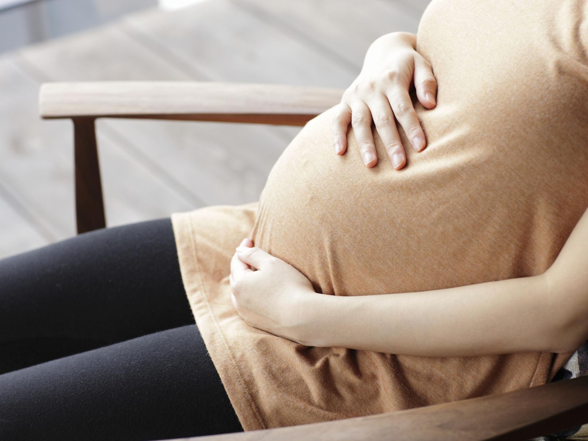 A pregnant women wearing skin top sitting on a chair