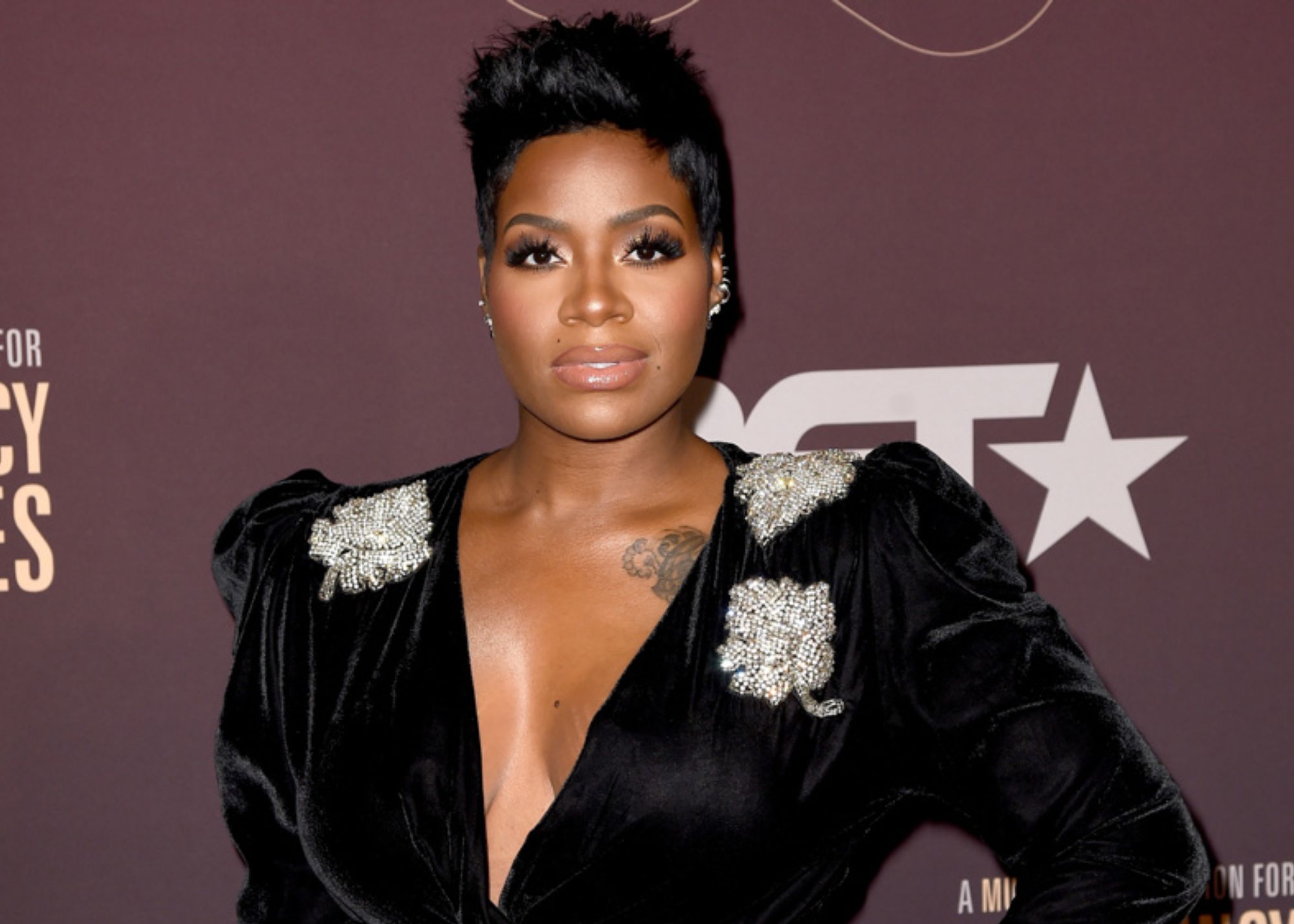 Fantasia Barrino is dressed in a gleaming black gown with crytal beads on the shoulder