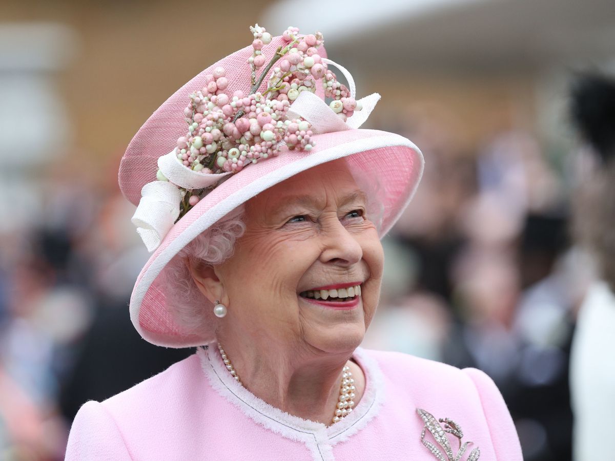 Queen Elizabeth wearing a pink outfit and smiling