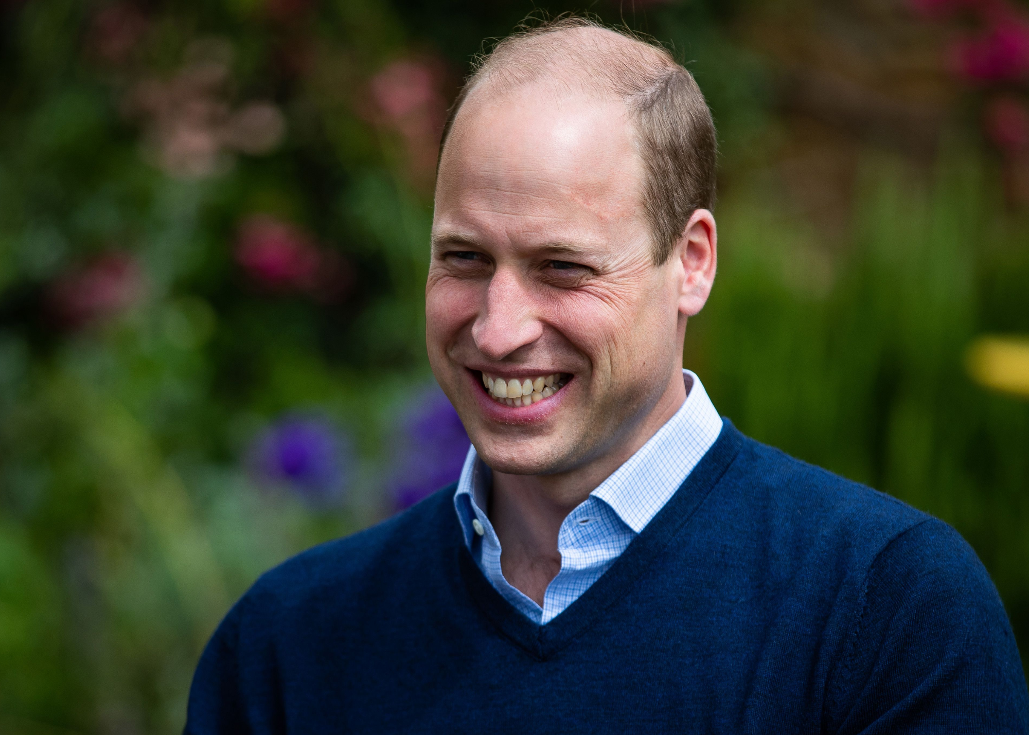 Smiling Prince William is attired in a blue v-neck shirt