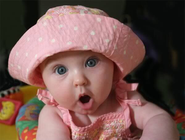 A baby wearing a pink dress and being surprised