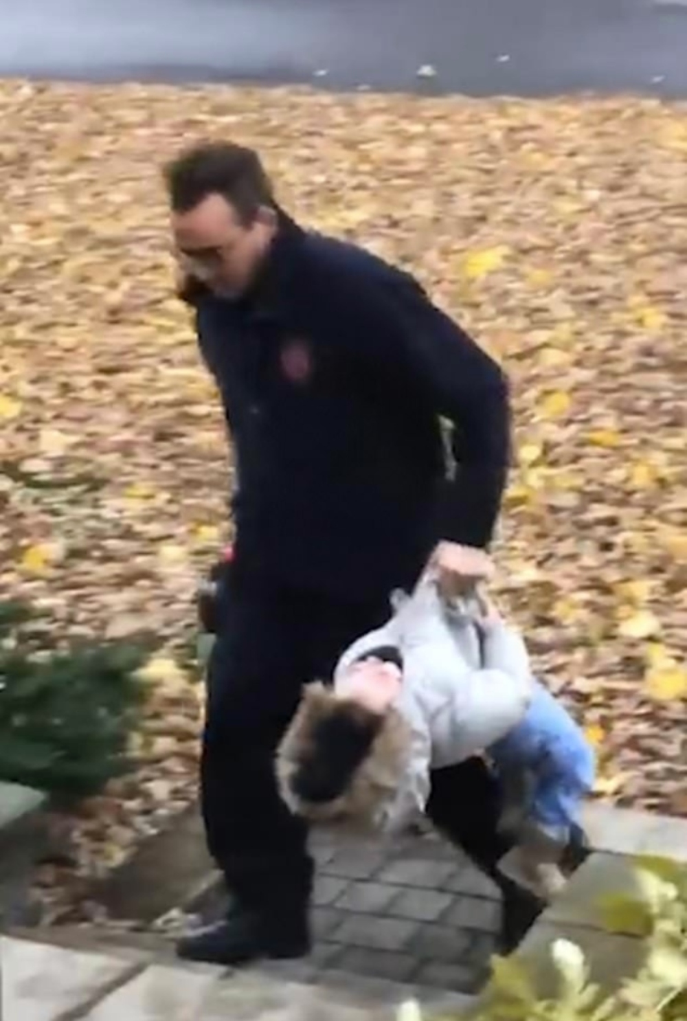 A father carrying his daughter by grabbing her jacket like a duffel bag