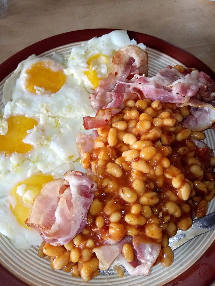 Fried eggs, bacon, and some beans by Carol C served on a plate