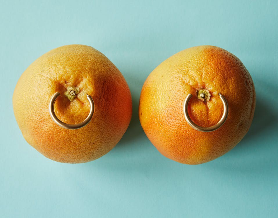 Two oranges on the table both with rings attached
