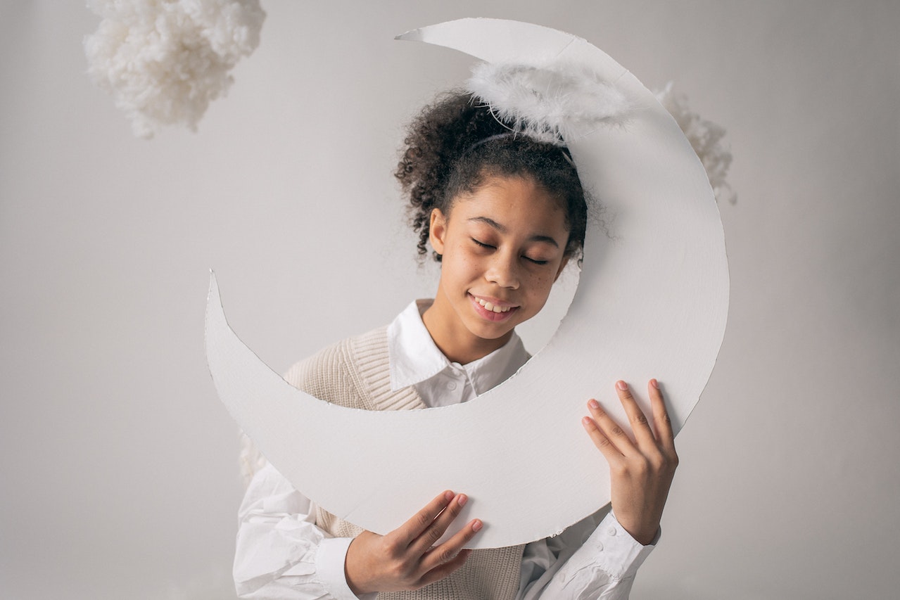 Smiling kid with eyes closed while holding a half moon decor