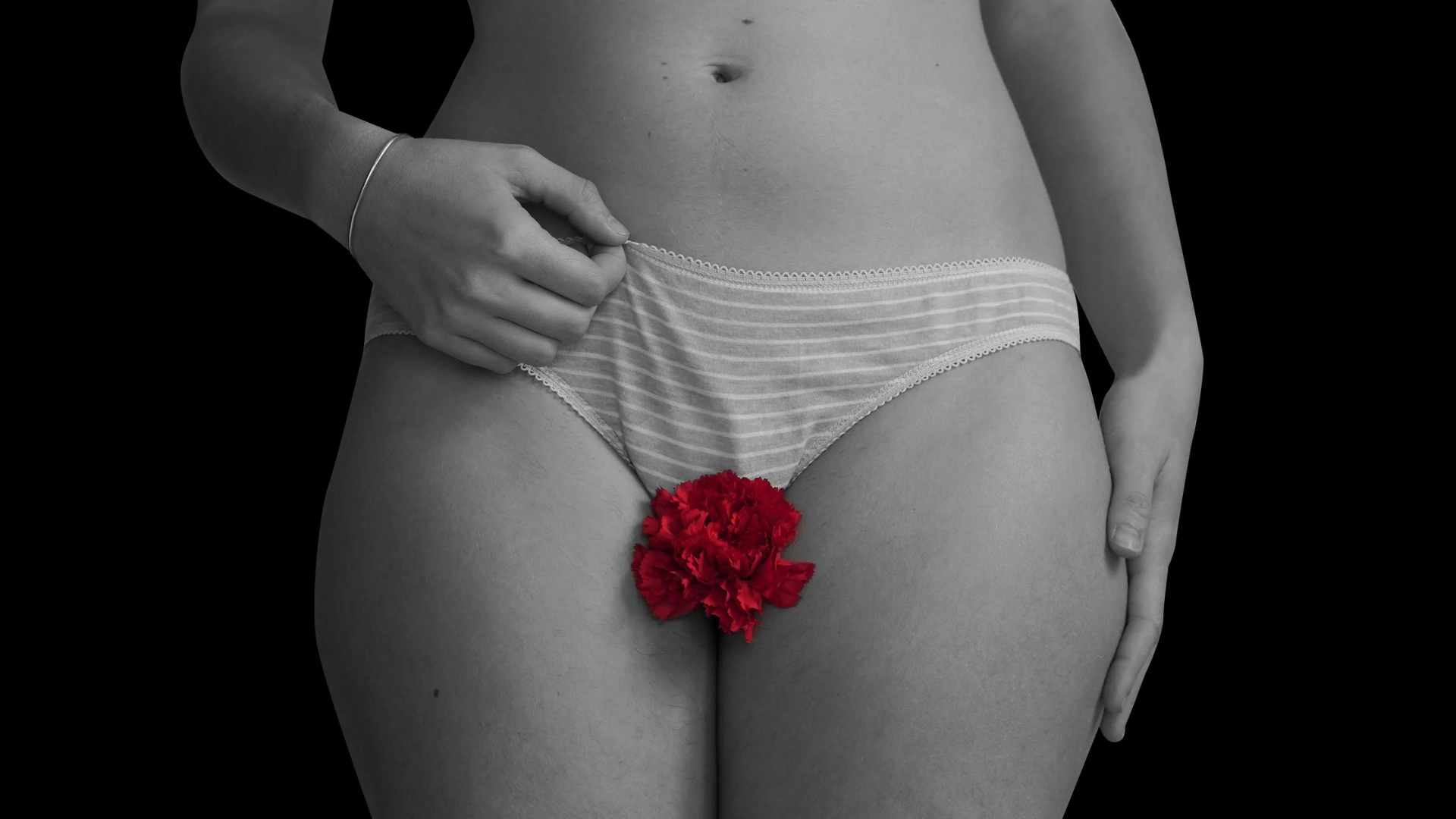 A standing woman with a red flower in front of her vagina