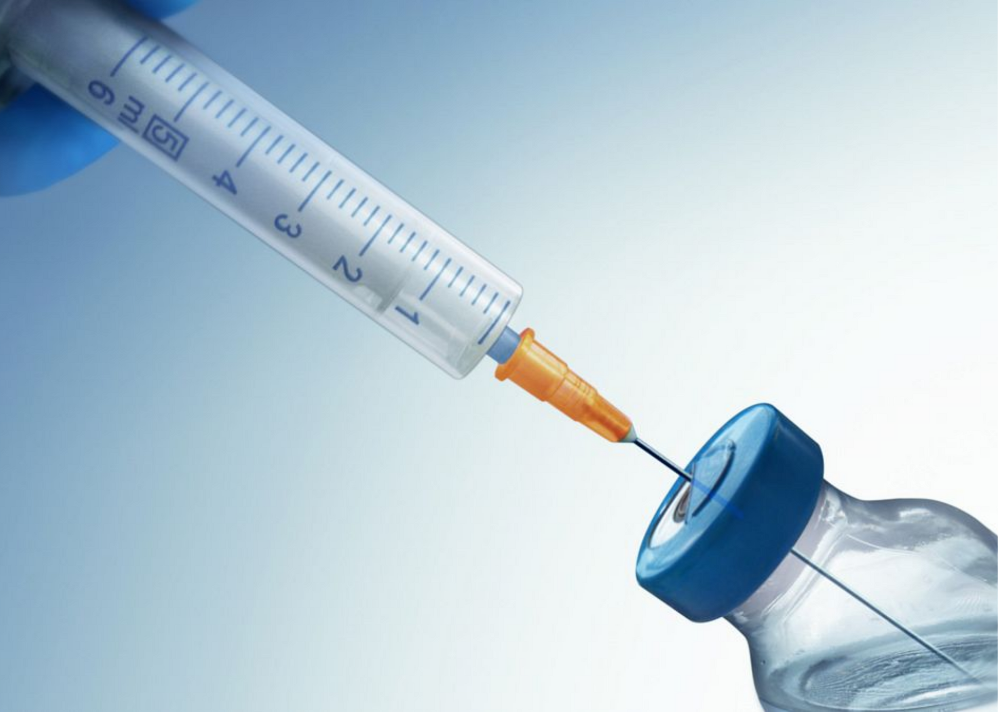A syringe is inserted into a small vial of liquid