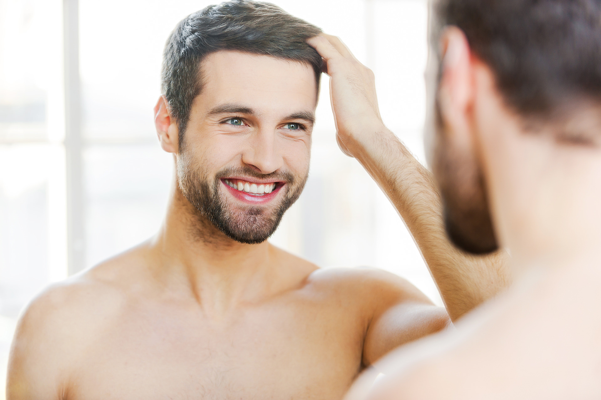 A man smiling in front of the mirror