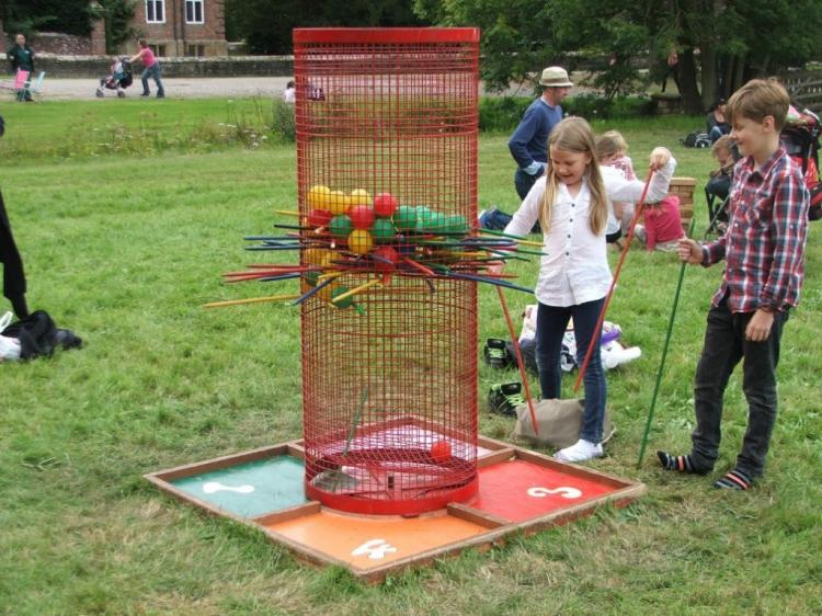 A girl and a boy playing the giant kerplunk game in the garden