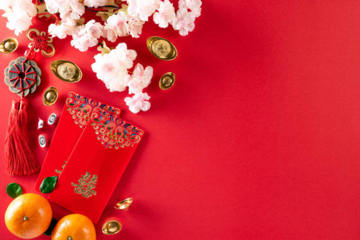 Oranges, red envelopes and other charms of good luck on a red surface