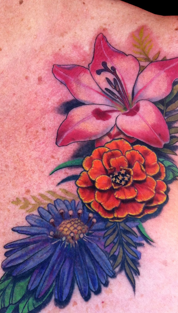 Blue aster flower, orange marigold and pink lily tattoo