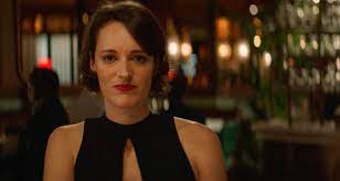 Phoebe Waller in a black dress sitting in a restaurant