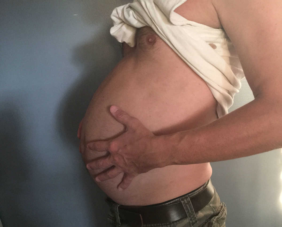 A Pregnant Man Looking At His Tummy
