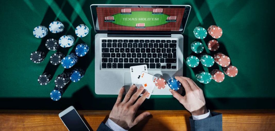 Casino tokens or chips, laptop placed on a green tabletop