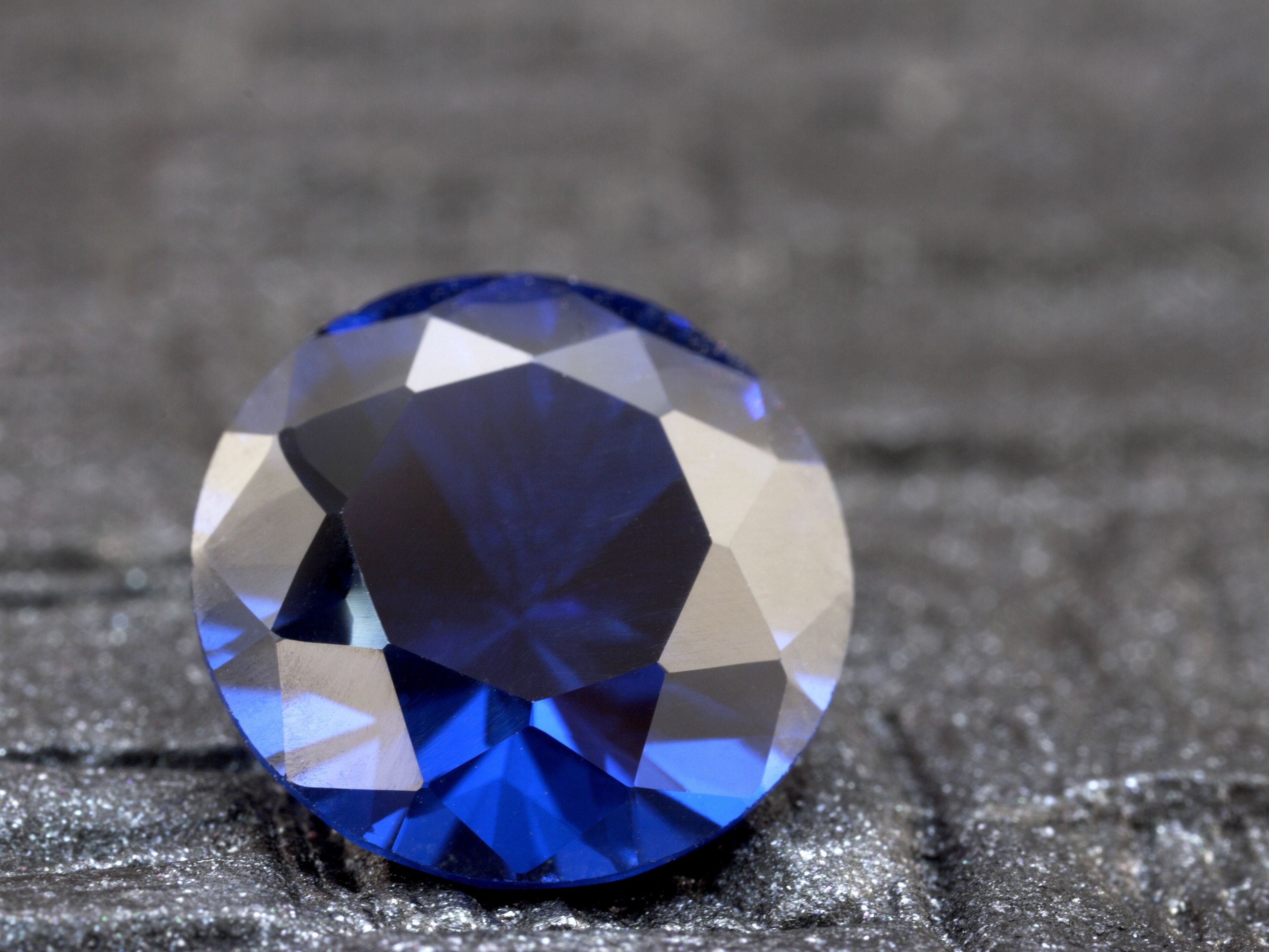 Round Sapphire stone placed on a grey surface