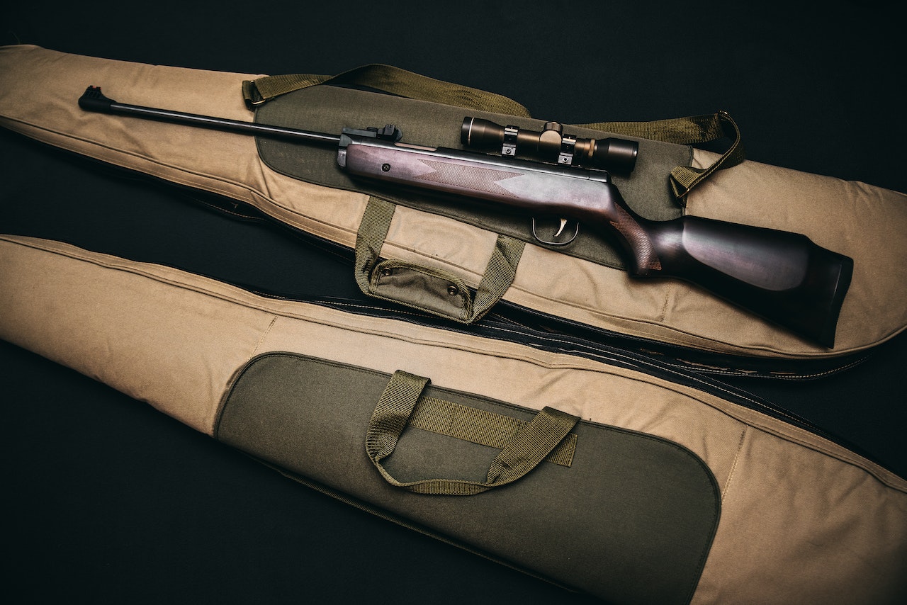 Black Rifle With Scope and Brown Gun Bag