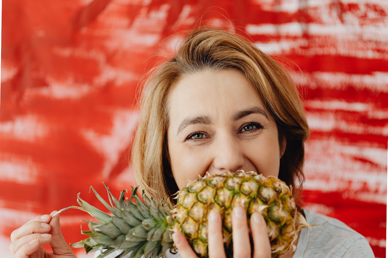 Woman Biting a Pineapple
