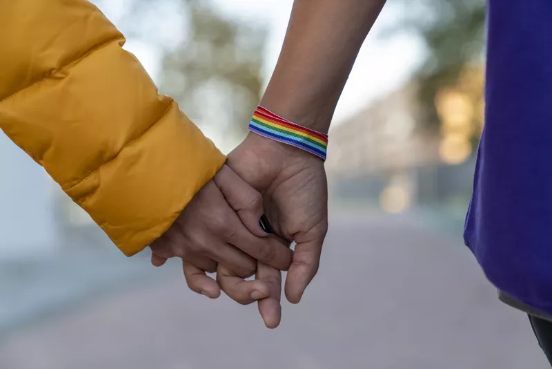 A Woman Holding Hands With A Man That Wears The Rainbow Bracelet