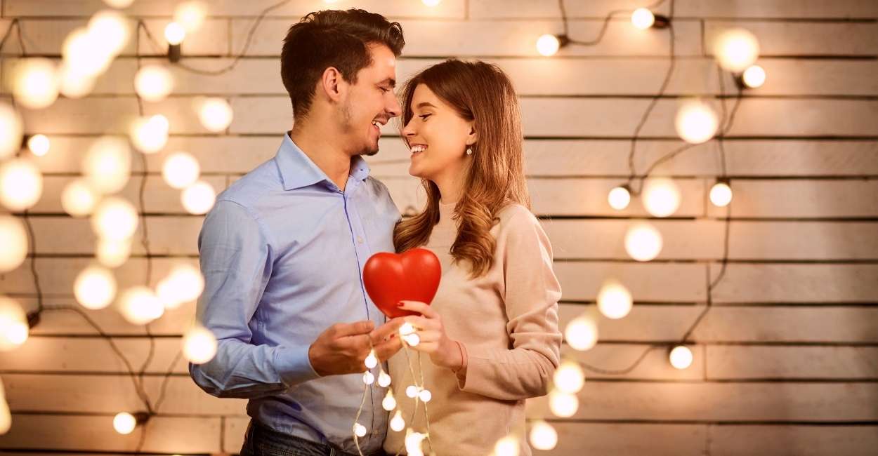 A couple is holding a heart sign and a light bulb