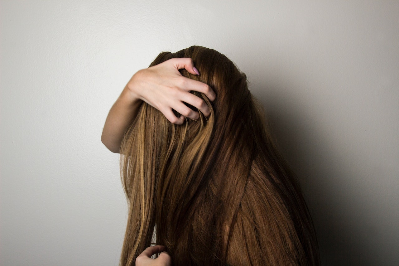 A Woman Covering Her Face with Her Long Brown Hair