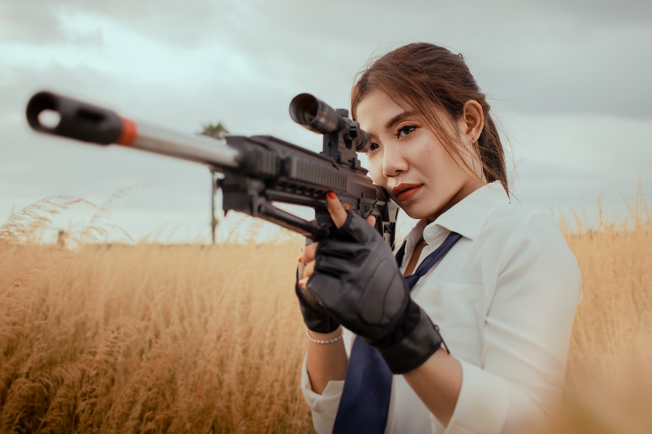 An Asian woman with rifle on grassy field