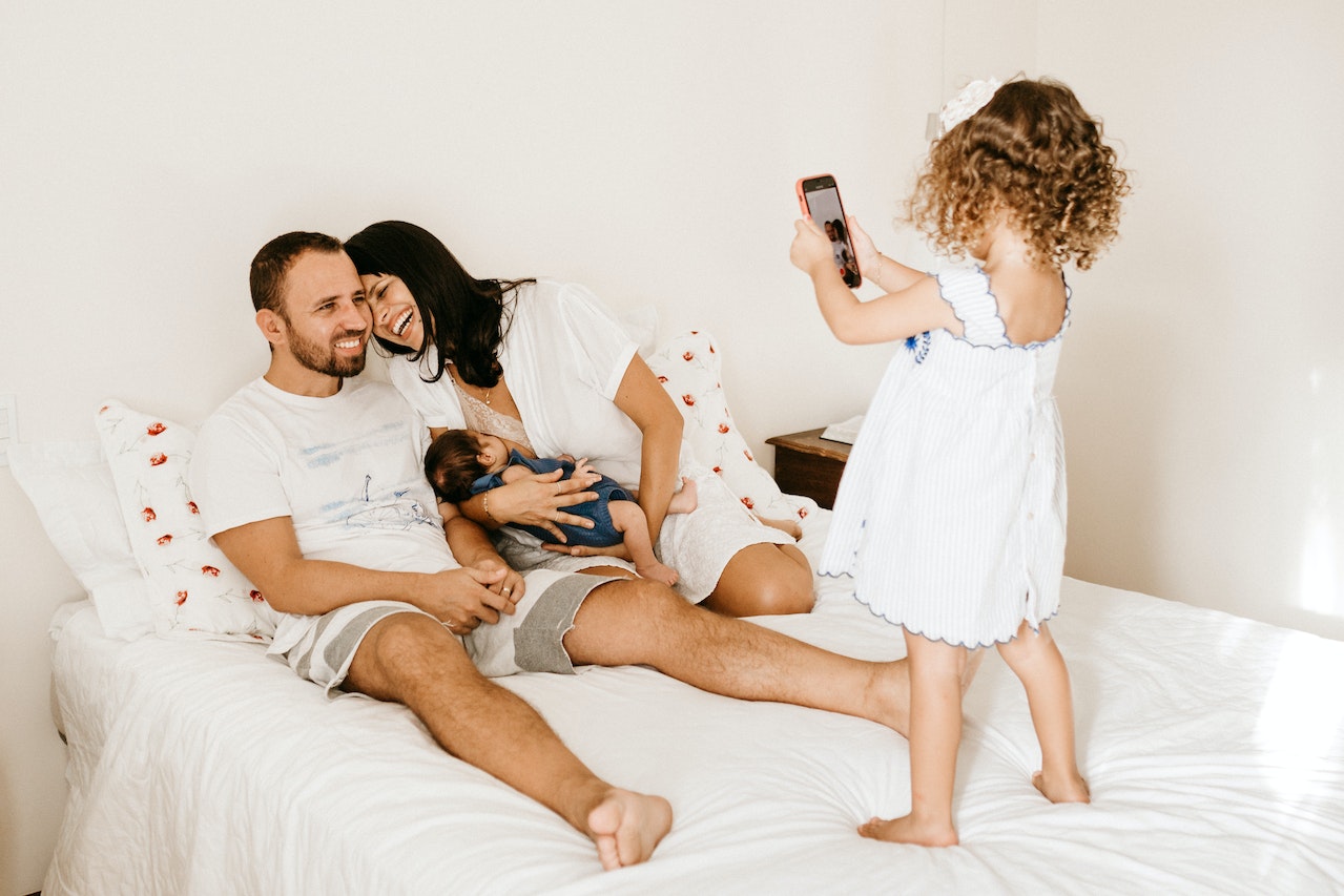 Toddler taking photo of her Parents using a smartphone