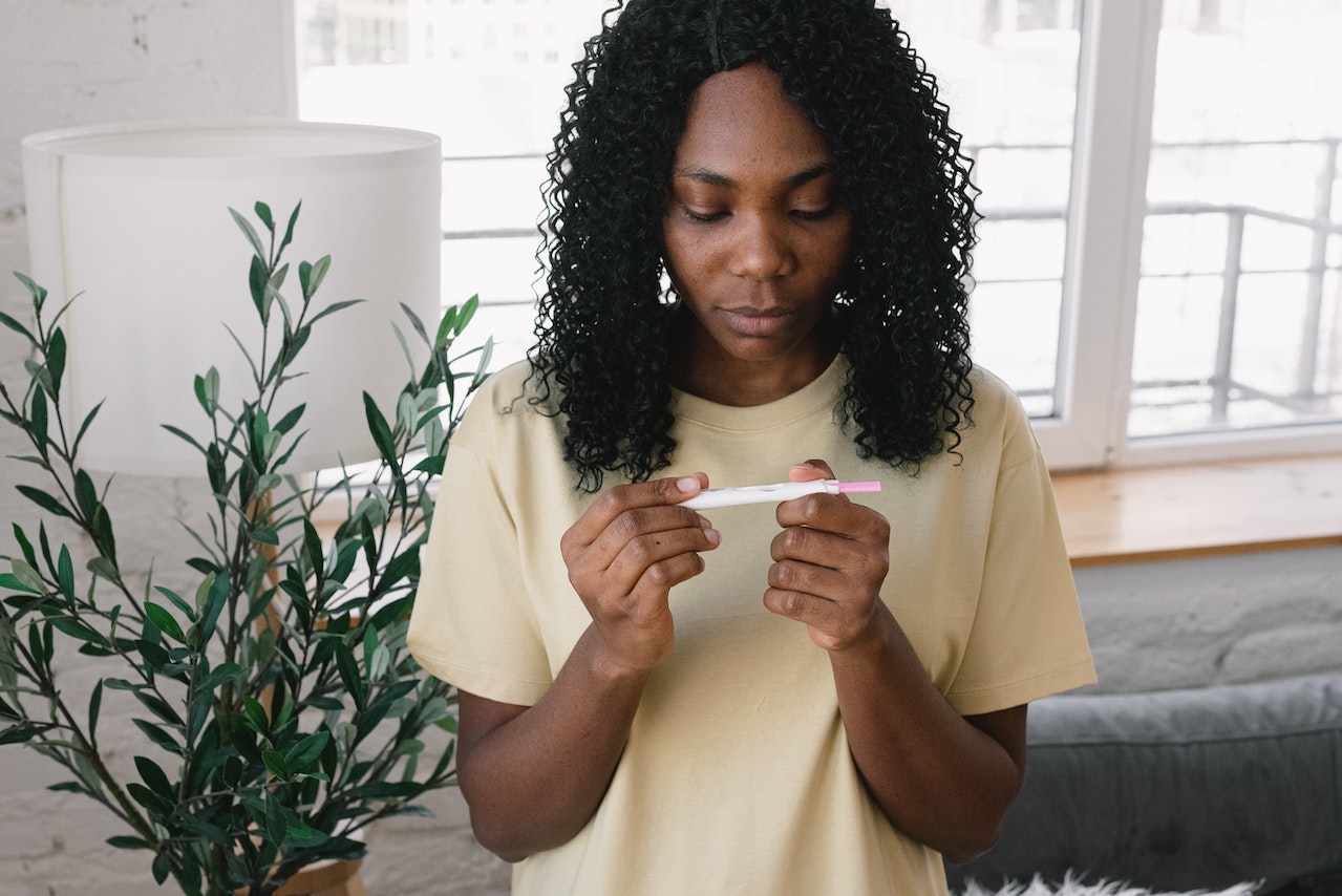 A black woman holding a pregnancy test