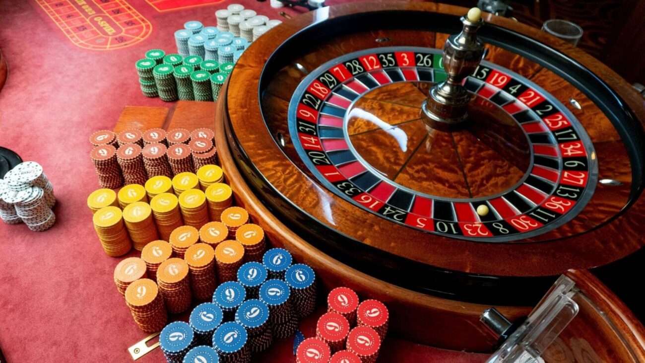 Casino roulette and casino coins on a red-carpted table