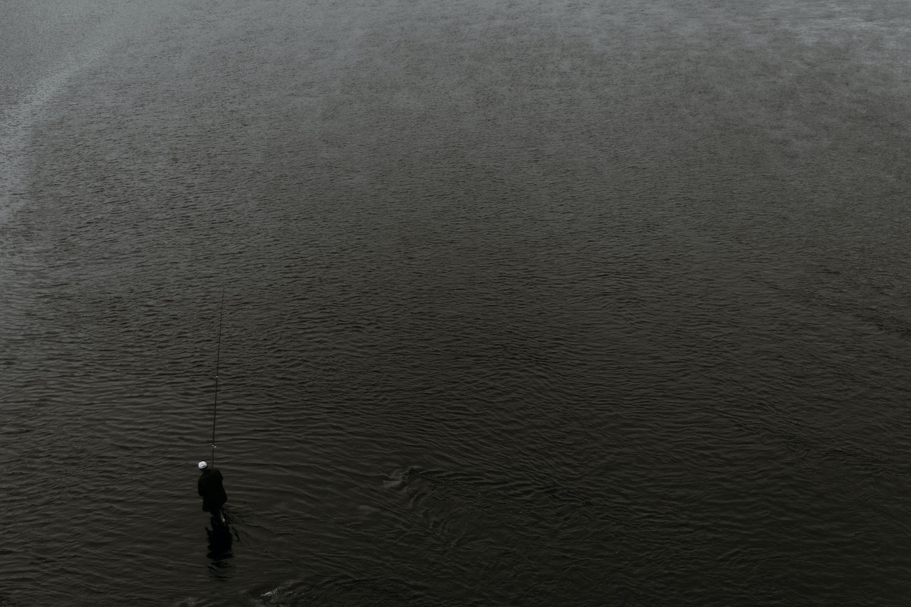 Anonymous fisherman standing in water with fishing rod
