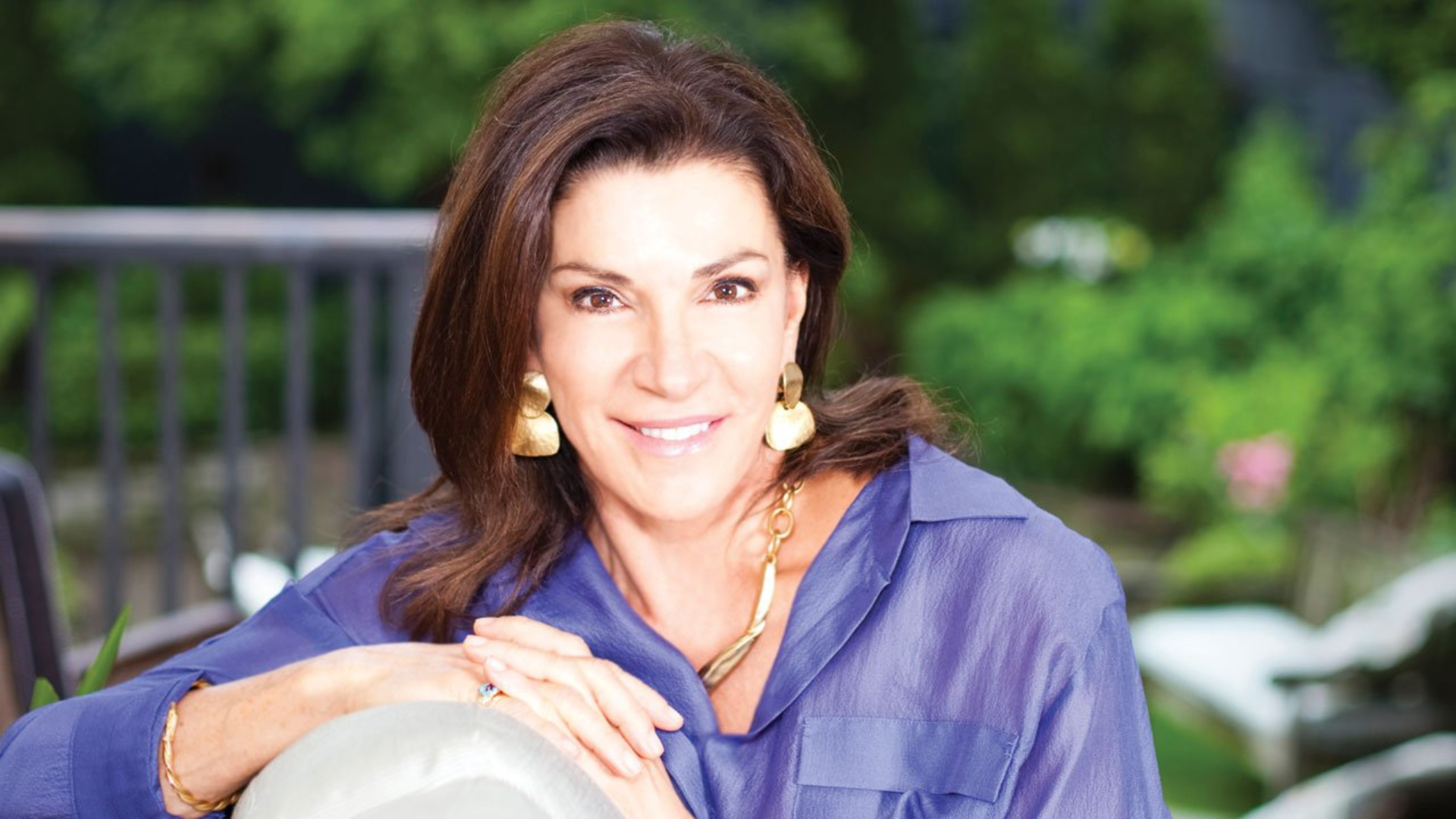 Hilary Farr wearing purple top while sitting on the couch