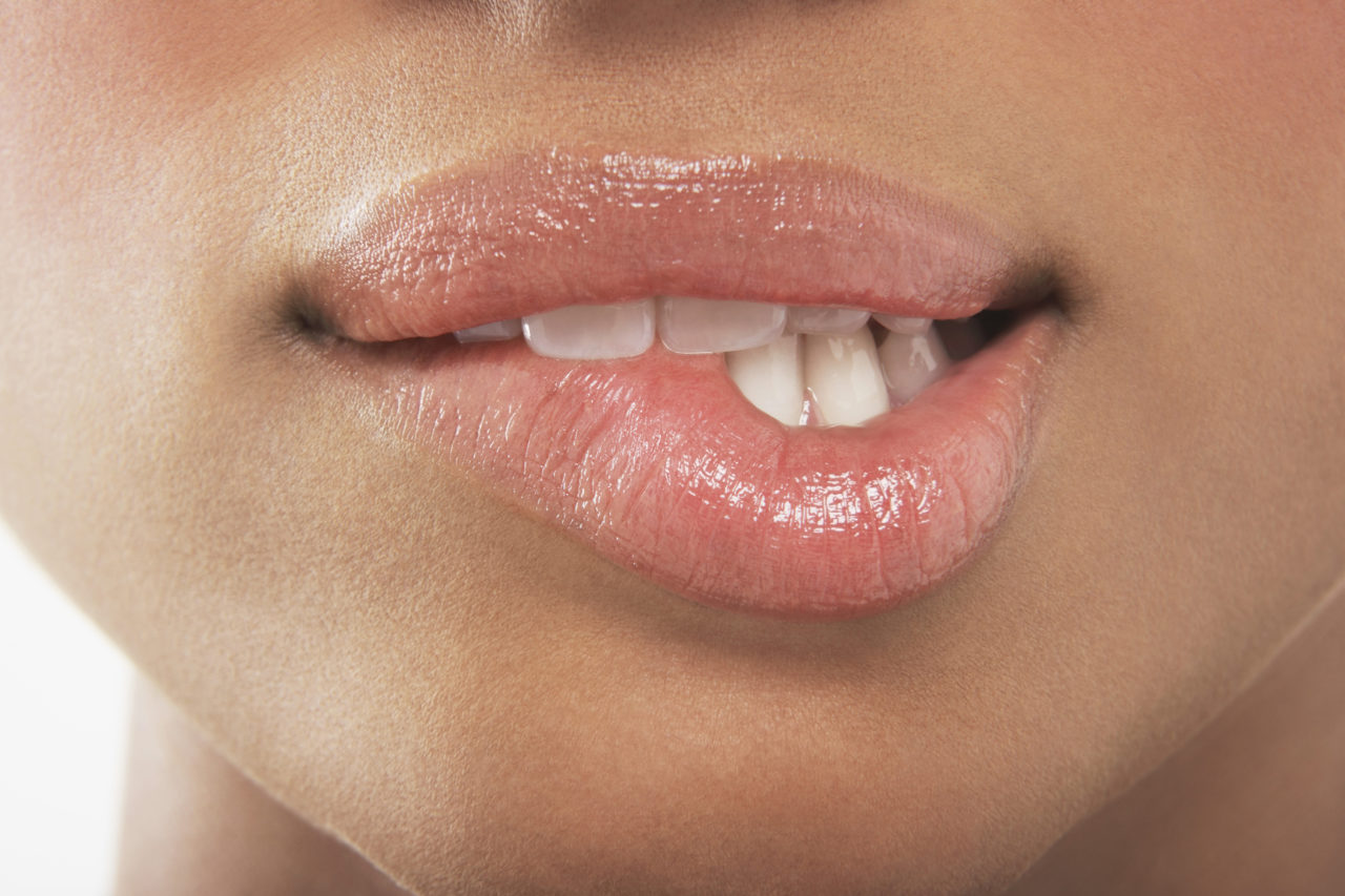 Woman with Shiny lips biting her lower lip 
