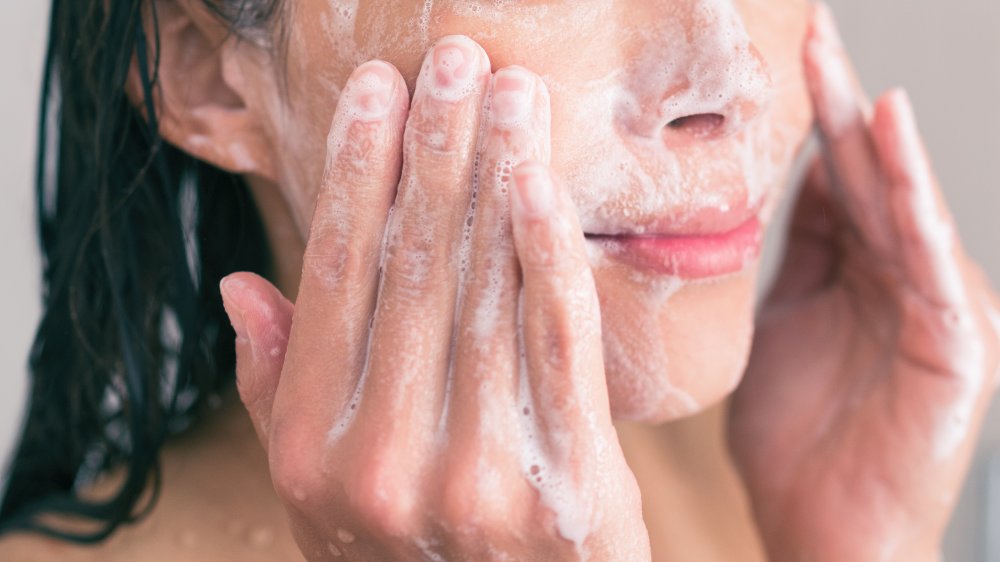 A woman massages her face gently while exfoliating her facial skin
