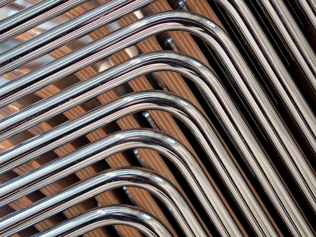 Close up of bended stainless steel tubes from chairs stacked in a pile