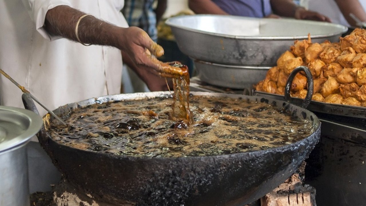 A man frying fritters using his own hands
