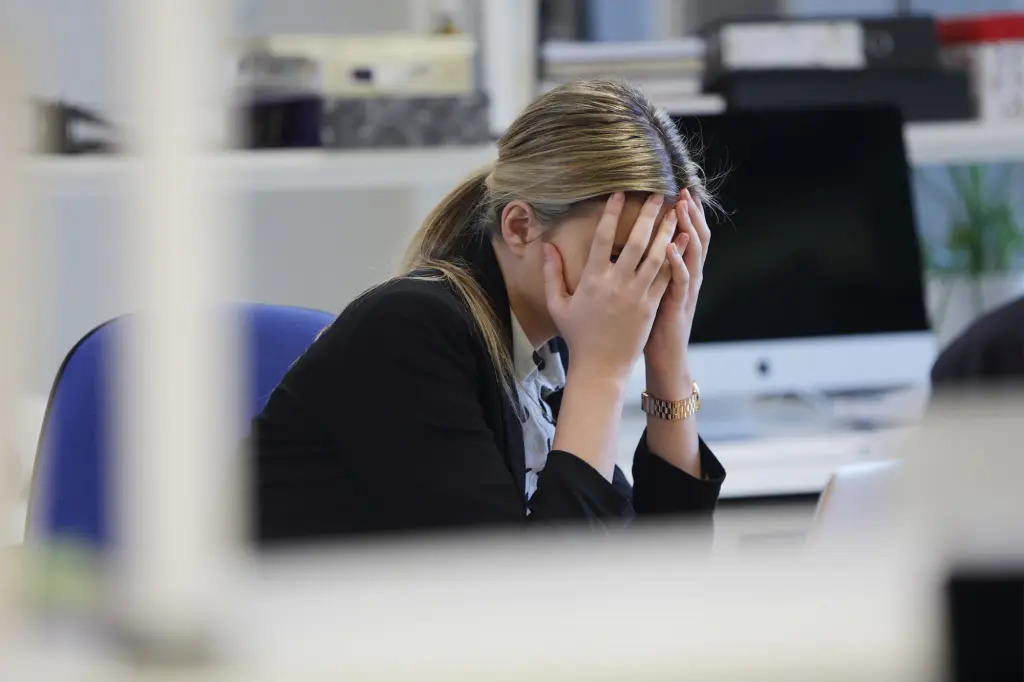 Woman in the office with her hands covering her face