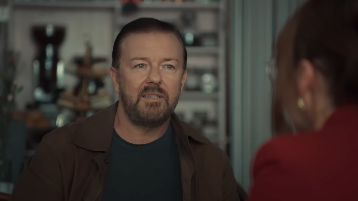 Ricky Gervais in a dark shirt under an open brown jacket in a scene in ‘After Life’