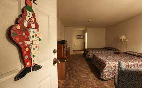 An opened door of clown motel room with a joker door-piece on it