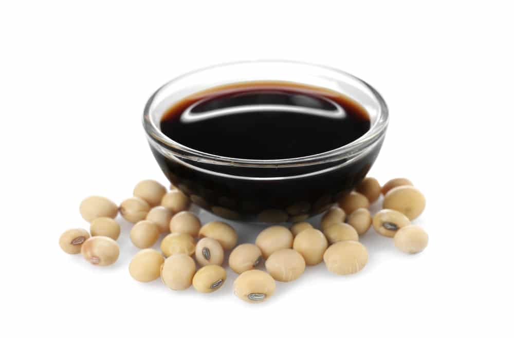 A bowl of Soy sauce next to soy beans